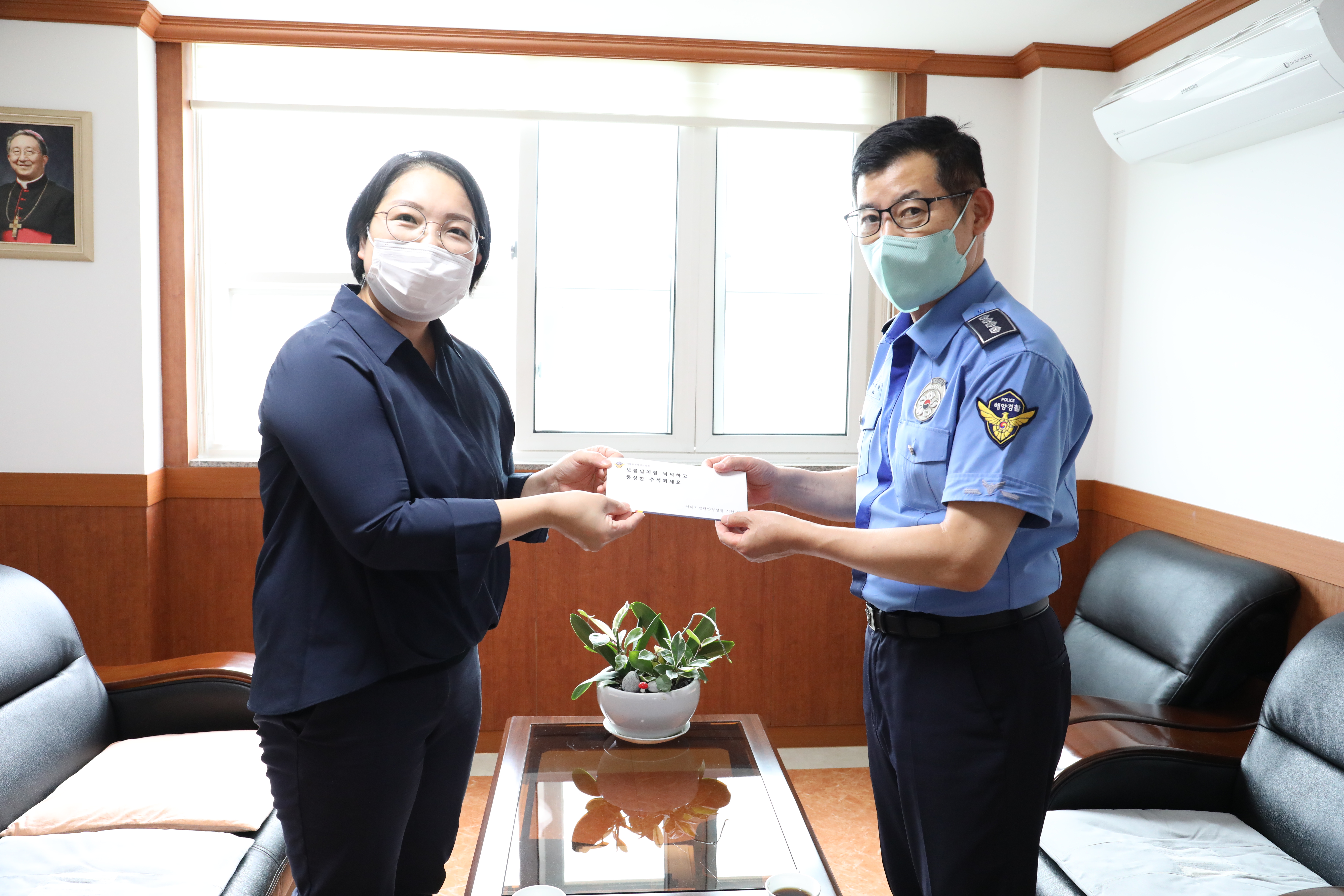 이재현(오른쪽) 서해지방해양경찰청 기획운영과장이 16일 목포 명도복지관에서 직원들이 모금한 사랑의 기금을 최미진 관장에게 전달하고 있다.